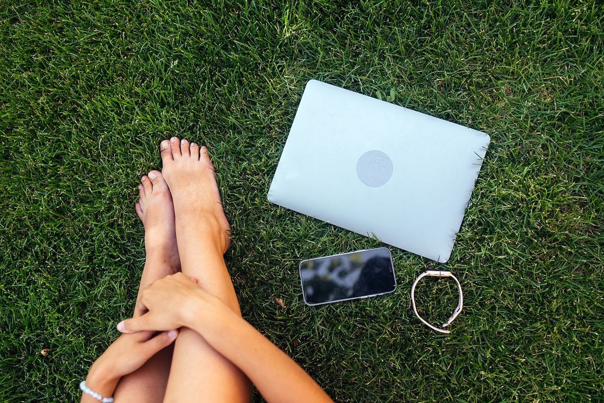 Bare feet with laptop outdoors.