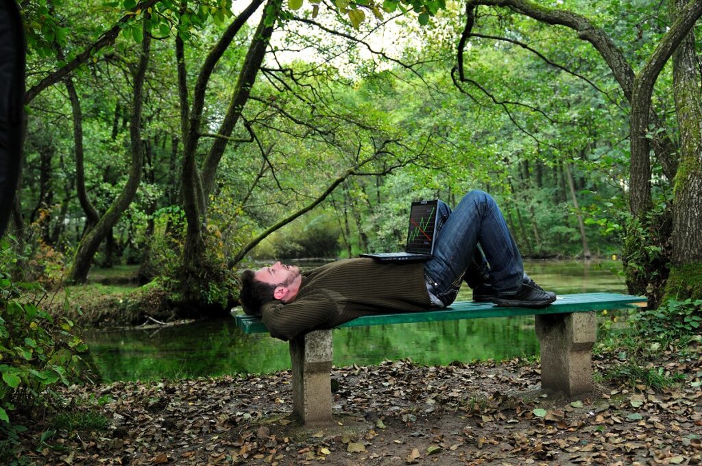 Man relaxing with laptop outdoors.