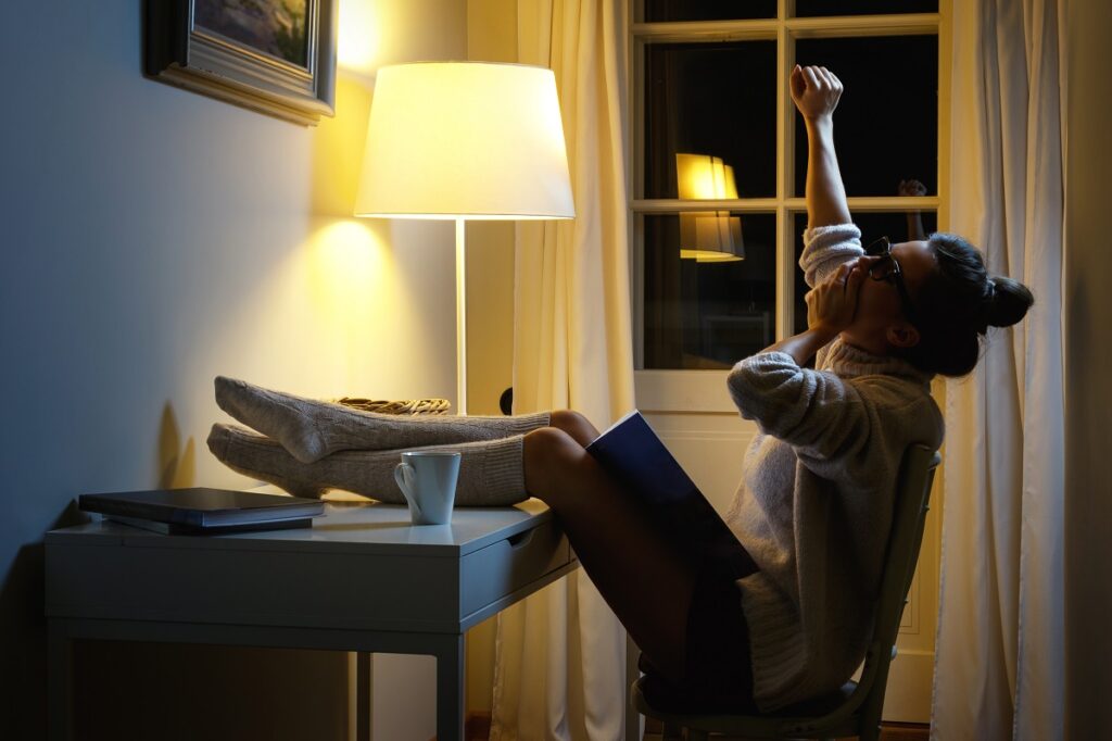 Woman reading and yawning at night